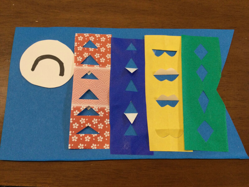 子どもの日の製作で折り紙をこいのぼりに貼っている写真