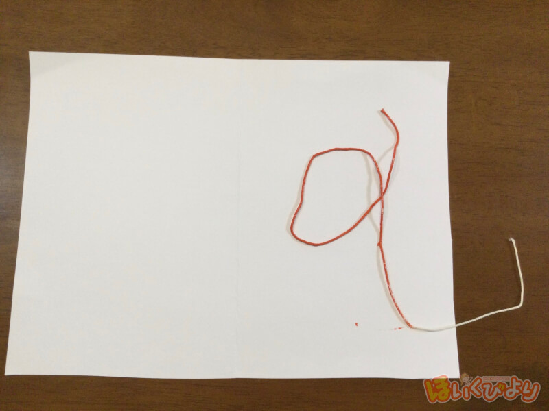 子どもの日の製作で画用紙に絵の具をつけたタコ糸を置いている写真