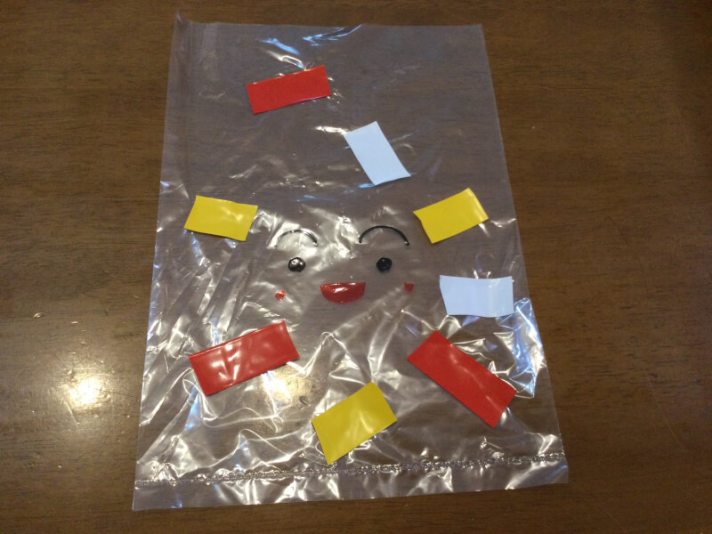 水遊び製作でビニール袋に顔を描いたりビニールテープを貼っている写真