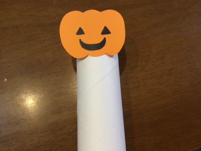 ハロウィンの製作でトイレットペーパーの芯にかぼちゃを貼り付けている写真
